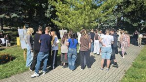 osoby stoją przy trawniku